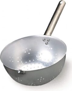 Dans les grandes trattorias italiennes, vous ne verrez jamais un chef vider une marmite entière d’eau bouillante dans l’évier pour récupérer ses pâtes. Le secret réside dans l'utilisation du Scaldapasta (littéralement « chauffe-pâtes »), une passoire demi-sphérique professionnelle munie d'un long manche et d'un crochet latéral ingénieux.